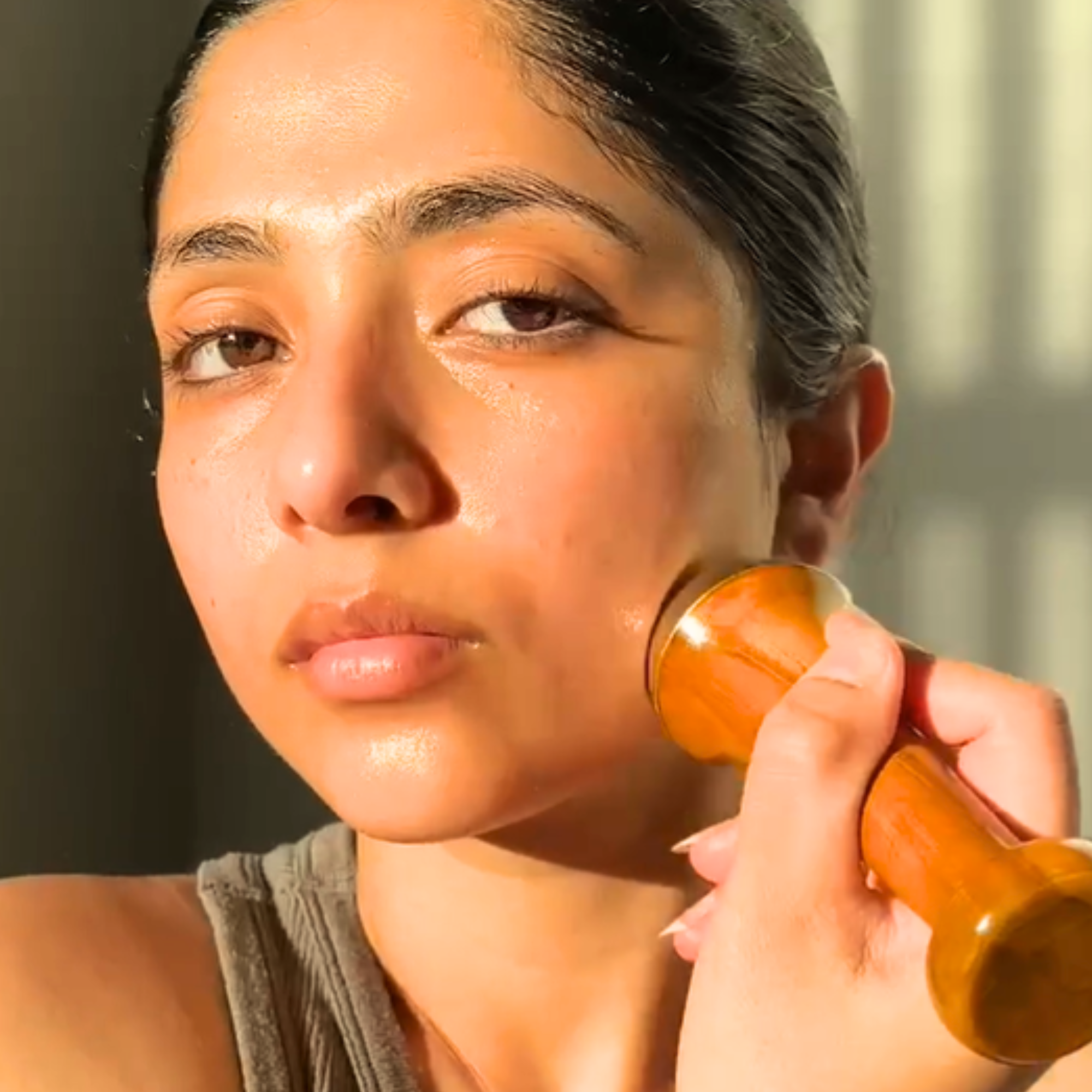 Girl holding Herbal Edge Kansa wand face massager ayurvedic gua sha for lymphatic drainage, blood circulation and anti aging
