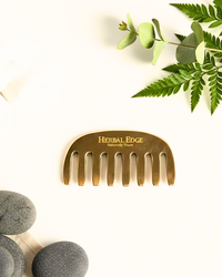 Gold kansa comb with 'Herbal Edge' branding on a white background with greenery and stones.
