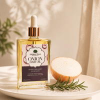 Herbal Edge Onion Hair Oil bottle with an onion and rosemary on a white plate