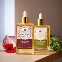 Two bottles of Herbal Edge Onion Hair Oil and moringa hair oil on a wooden surface with a neutral background.