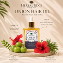 A bottle of Herbal Edge Onion Hair Oil is displayed on a marble slab with decorative ingredients including red hibiscus flowers, green amla fruits, rosemary, and a green leaf, set against a warm beige background with soft leaf shadows. Text overlays highlight key ingredients.