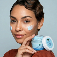 Woman applying cream to her face with a jar of Herbal Edge Jojoba Face Cream.