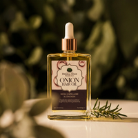 Herbal Edge Onion Hair Oil bottle with dropper on a blurred green background and rosemary on the side